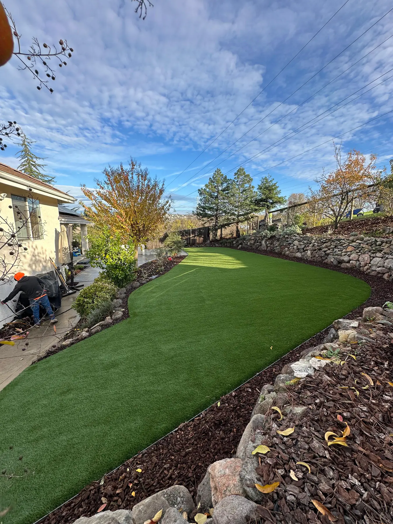Curved artificial turf lawn with rock border and plants