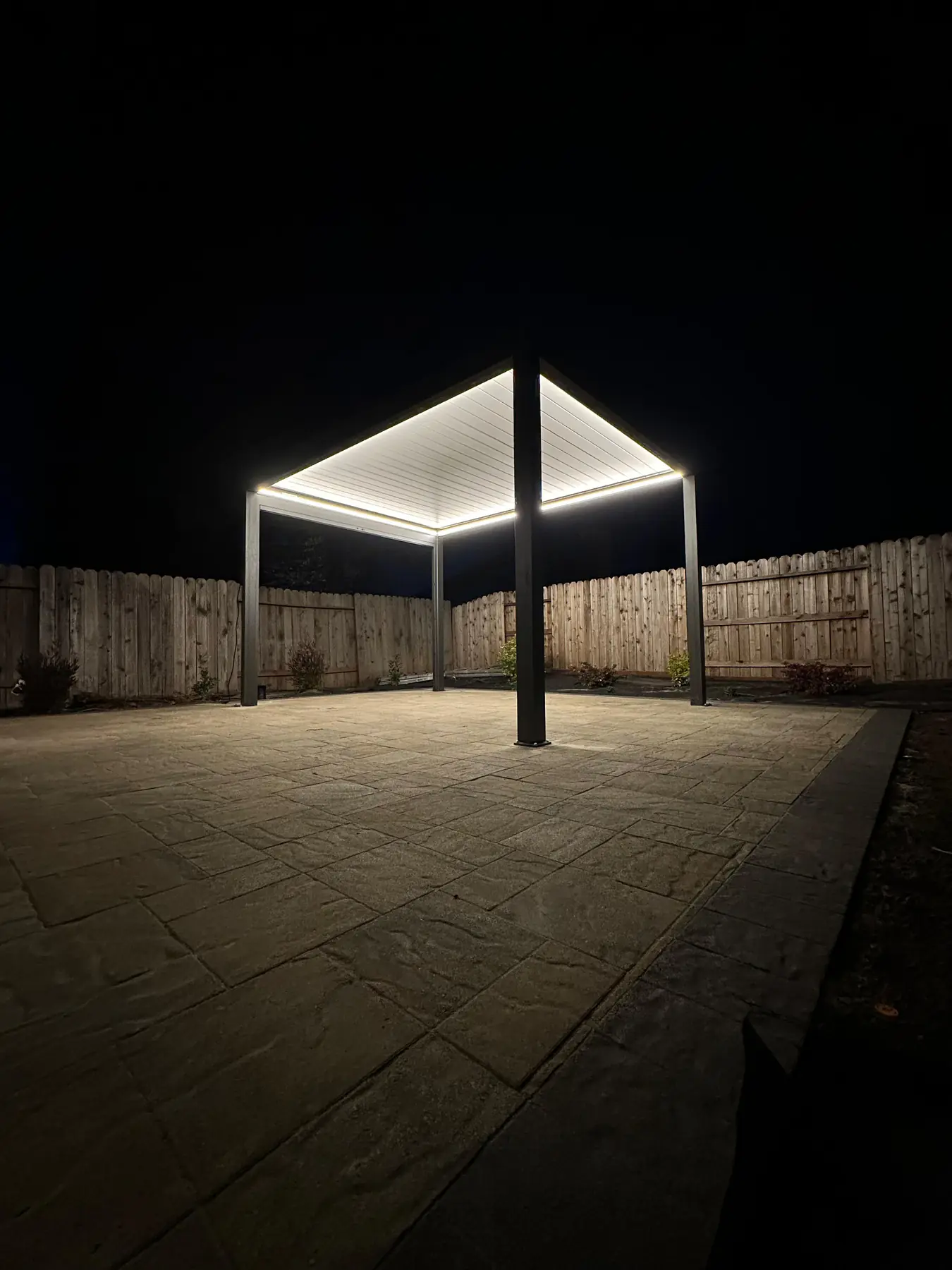 Pergola and concrete patio illuminated at night