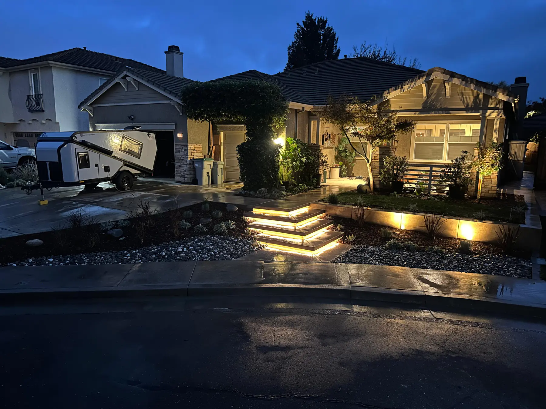 Front yard landscape with warm lighting and steps at night