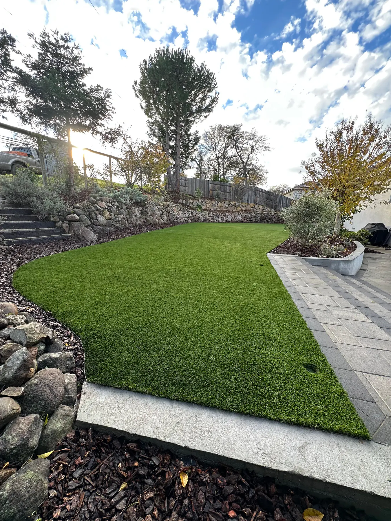 Artificial turf bordered by boulders and mulch