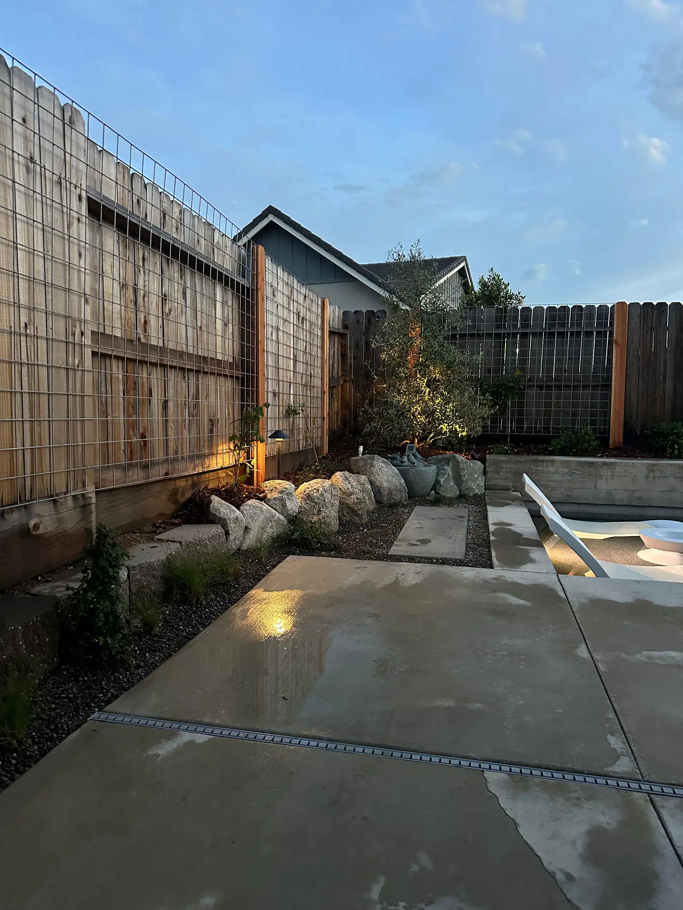 Boulder garden and fence with warm lighting