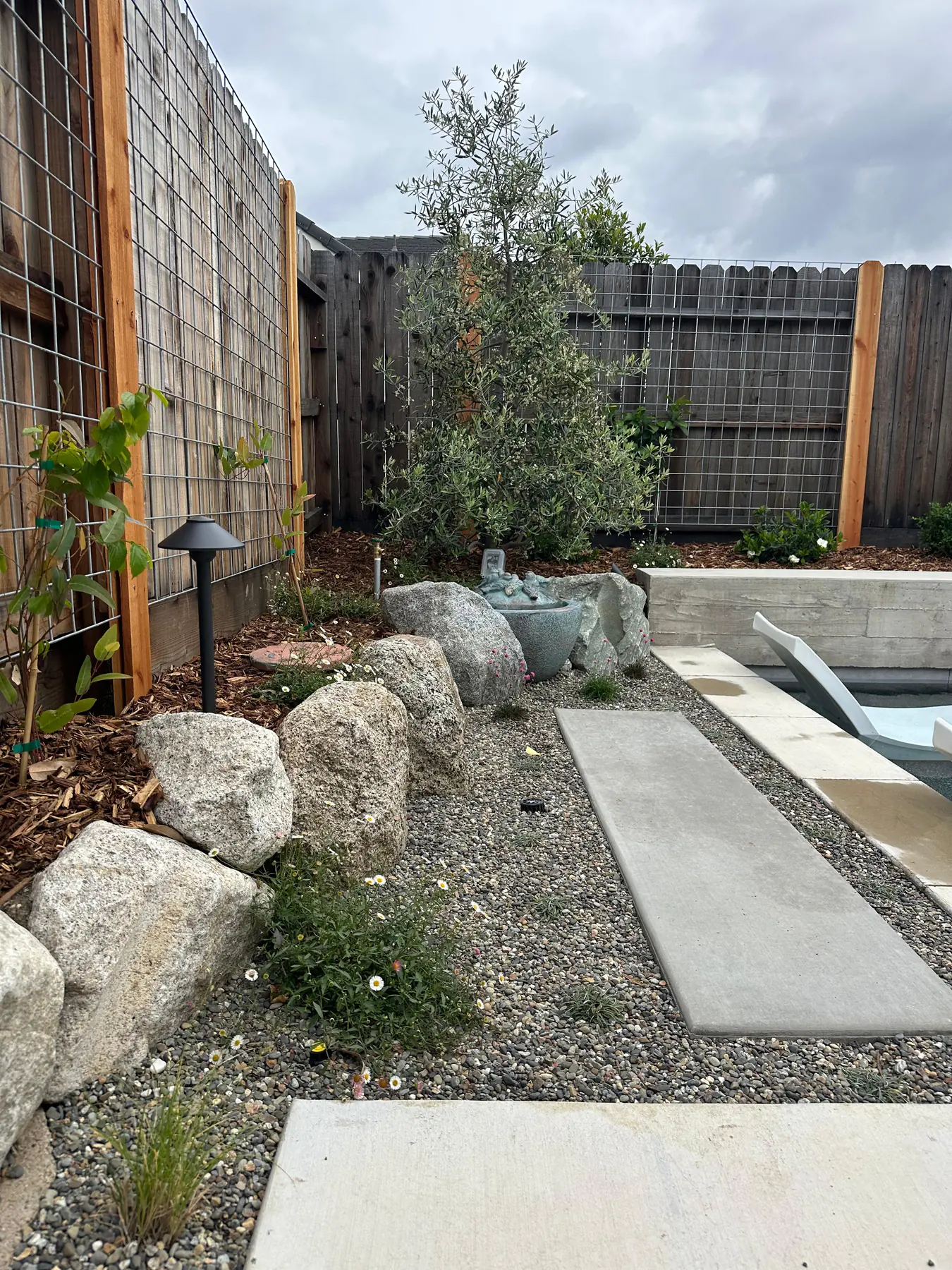 Decorative water feature garden with rocks, gravel, and path slabs